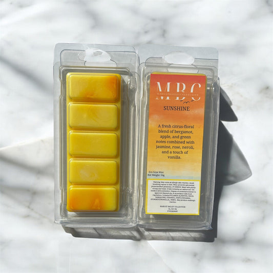 Packaged yellow wax melts with an orange label on a marble surface called sunshine